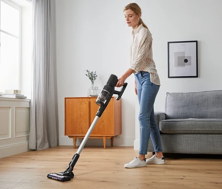 Frau saugt mit einem digitalen Akkusauger den Boden.