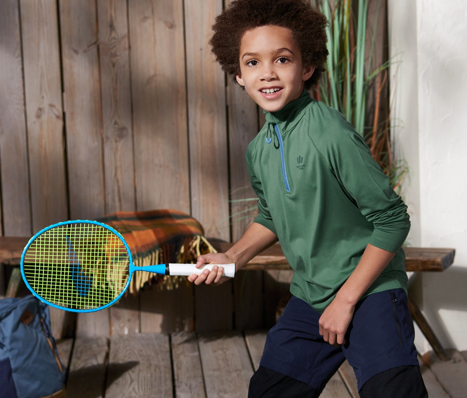 Junge spielt Badminton im grünen Funktionsshirt.