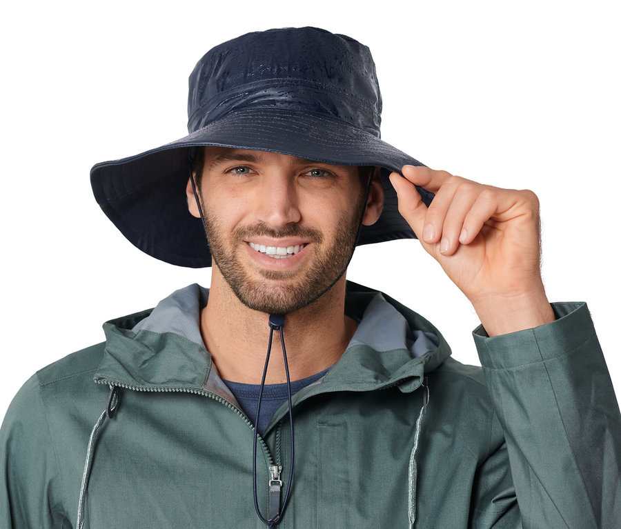 Mann lächelt und hält die Krempe eines Unisex-Regenhuts fest.