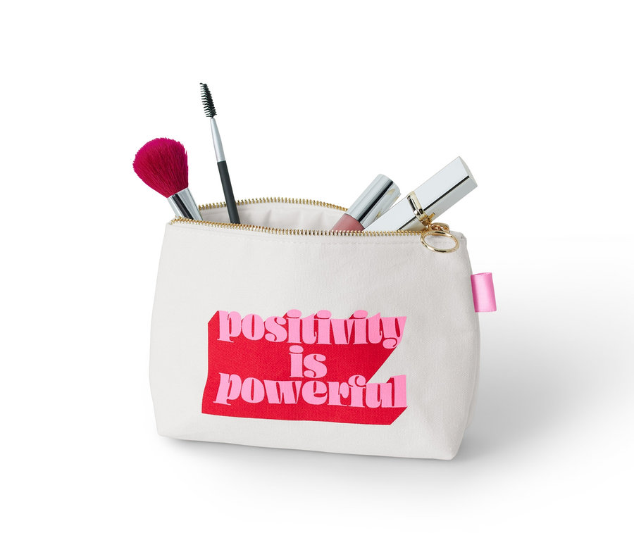 Eine Kosmetiktasche mit dem Aufdruck "positivity is powerful" und Kosmetikpinsel.