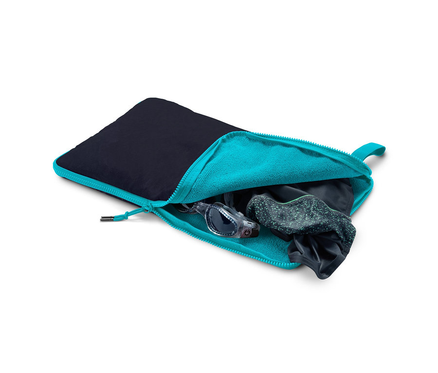 Ein offener, blau-türkisfarbener Reißverschlussbeutel mit schwarzem Stoff oben, im Inneren befinden sich eine Schwimmbrille und Kleidung. Umzieh-Unterlage und Nasssack.