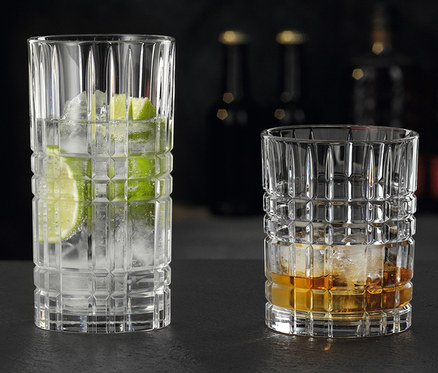Zwei Gläser stehen auf einem Tisch. Eines ist ein Nachtmann Longdrinkglas »Highland« mit Wasser, Eis und Limette, das andere ist ein Nachtmann Tumbler »Highland« mit Whisky und Eis.