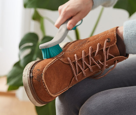 Frau reinigt braunen Schuh mit 2-in-1-Grobschmutz-Schuhreinigungsbürste.