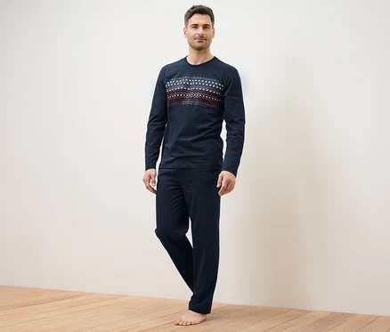 Mann steht und trägt einen dunkelblauen Pyjama.