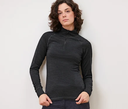 Frau posiert in anthrazitfarbenem Funktionsshirt mit RWS-zertifizierter Wolle und dunkler Hose.