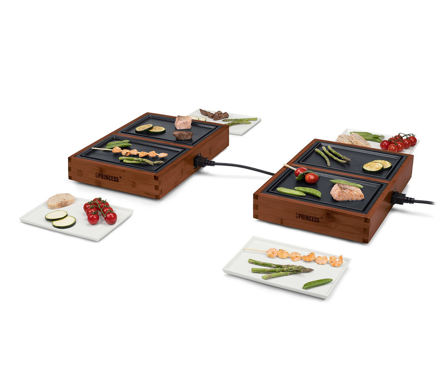 Zwei Tischgrills »Dinner4All« mit vorbereiteten Zutaten zum Grillen.