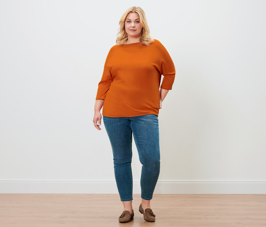 Frau posiert in orangefarbenem Feinstrickpullover, Treggings »Fit Nelly« und Loafer aus Veloursleder.