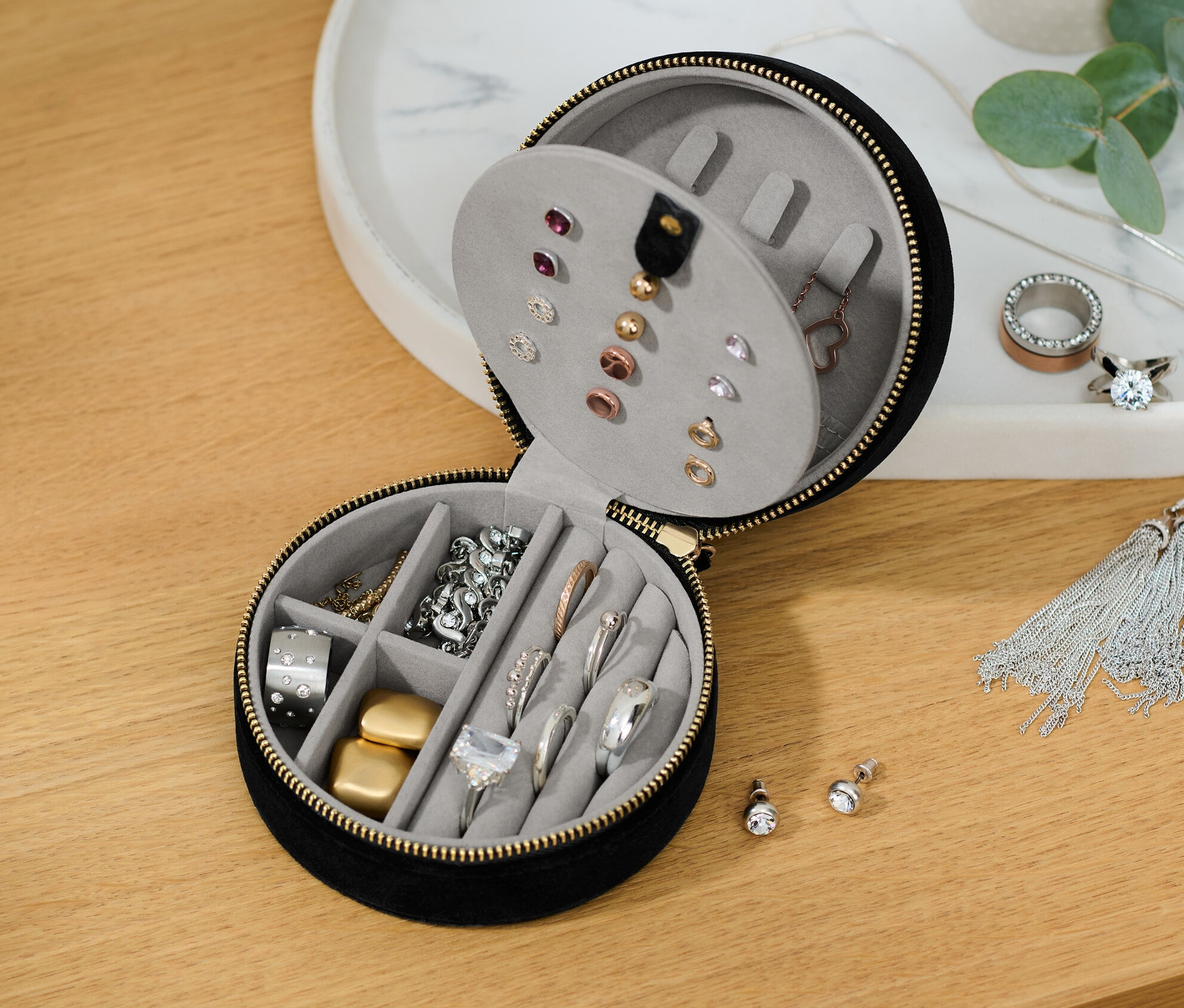 Eine teilweise geöffnete kleine Schmuckdose mit verschiedenen Schmuckstücken darin.
