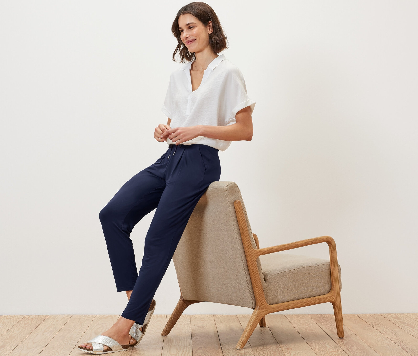 Frau sitzt auf einem Stuhl und trägt eine dunkelblaue Jerseyhose.