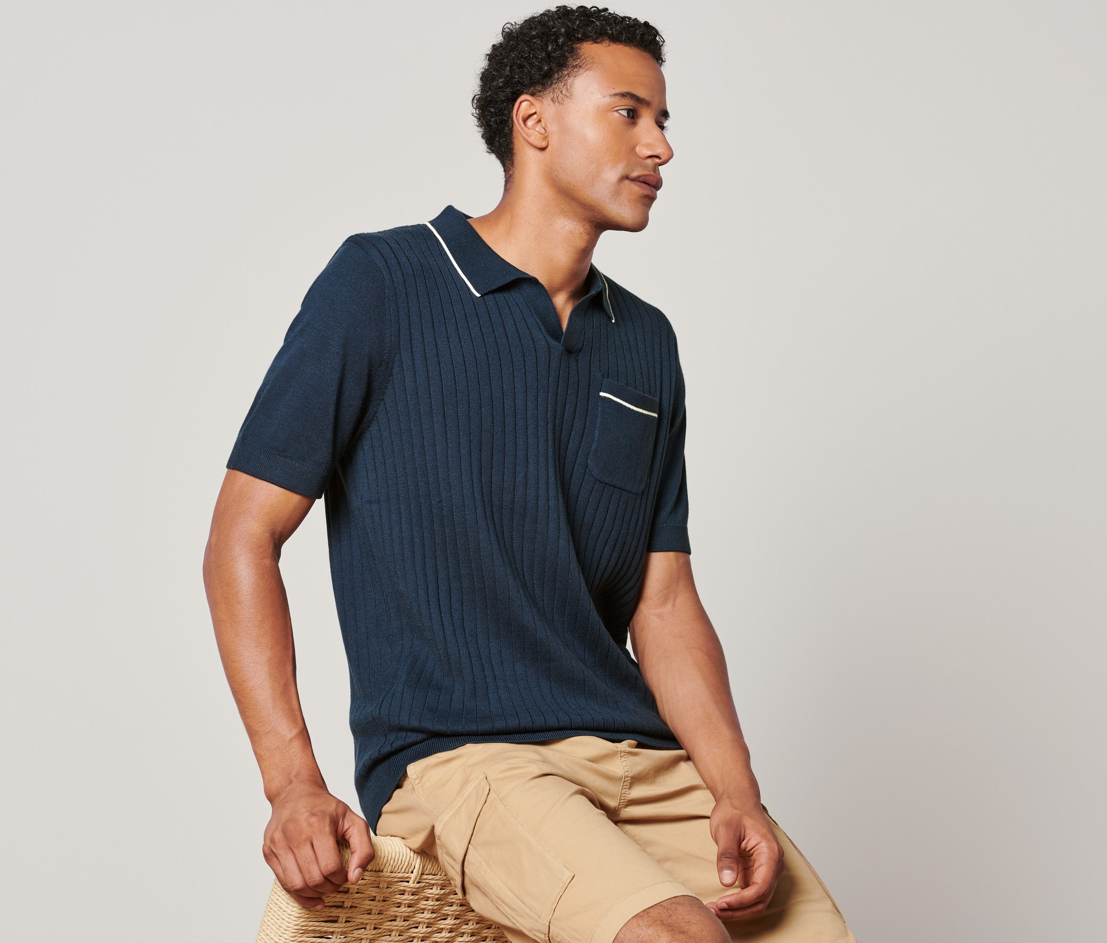 Mann sitzt und trägt ein Poloshirt.