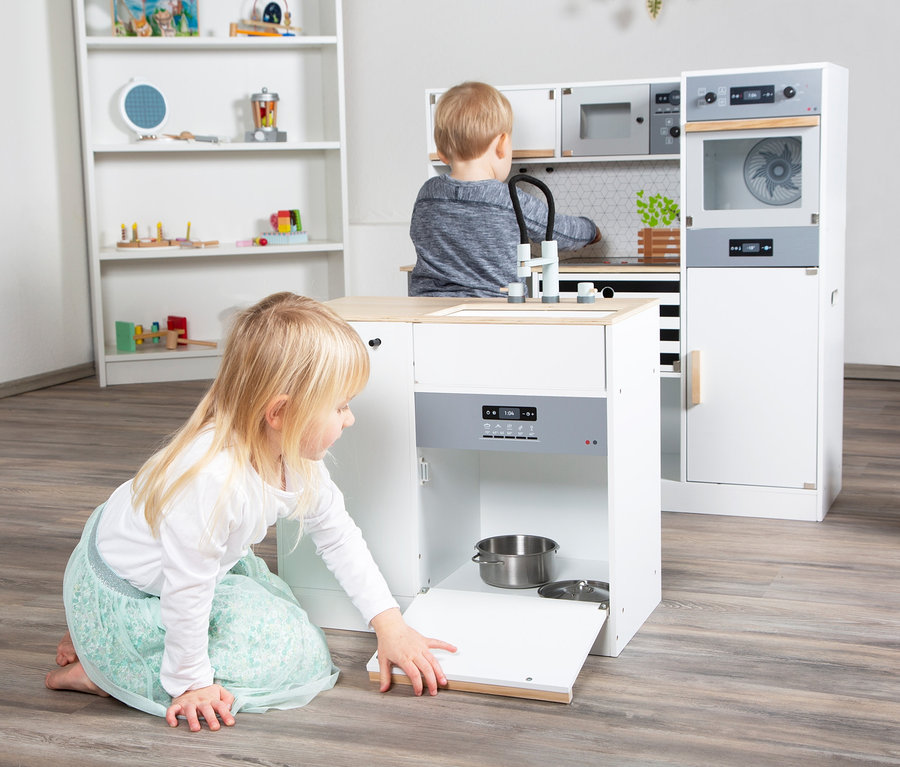Mädchen spielt mit small foot Kinderküche modular XL, öffnet die Tür, in der sich ein Topf befindet.