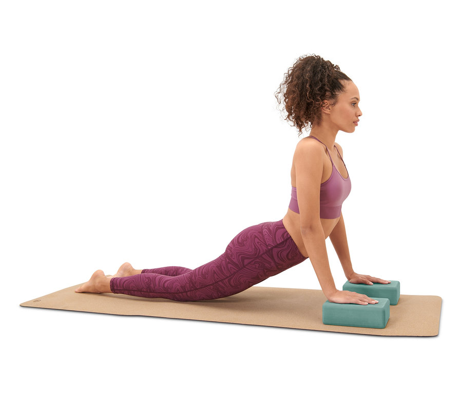 Frau macht Kobra-Pose auf einer Yogamatte mit Yoga-Set.