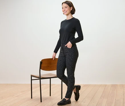 Frau posiert neben einem Stuhl und trägt eine bedruckte Bengalin-Hose.