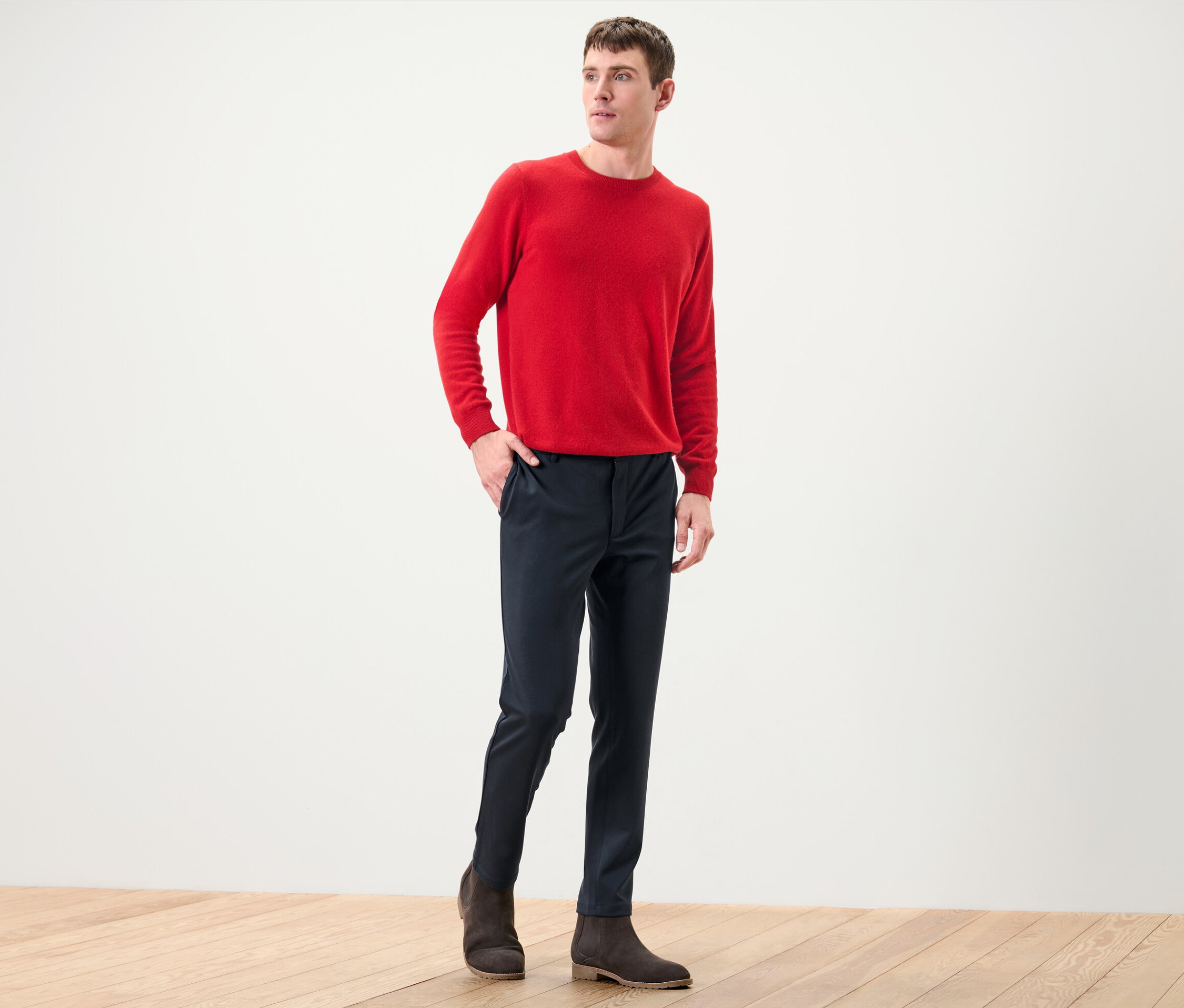 Mann posiert in rotem Pullover und marineblauer Comfort-Stretch-Hose.