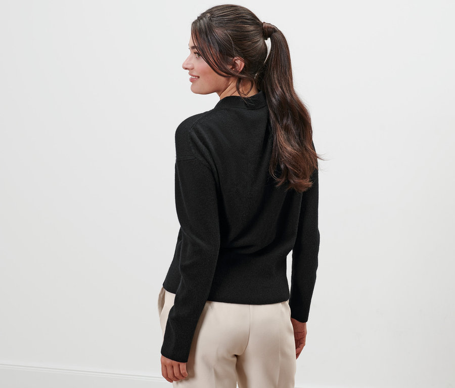 Frau blickt über die Schulter und trägt einen schwarzen Feinstrickpullover mit Cashmere.