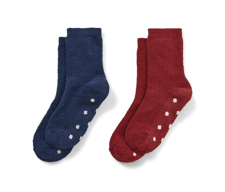 Zwei Paar Kinder-Kuschelsocken: ein Paar dunkelblau, ein Paar rot, jeweils mit weißen Sternen.