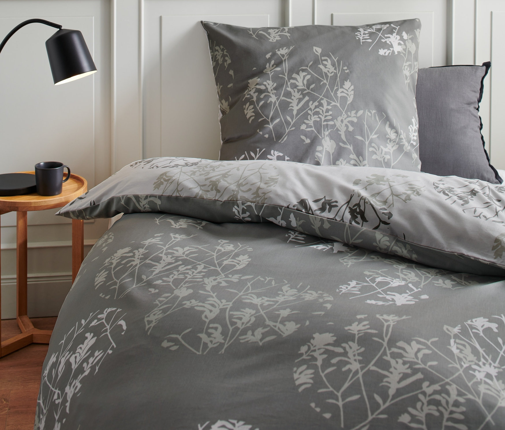 Graue Premium-Baumwoll-Bettwäsche Normalgröße mit Blumenmuster auf einem Bett.