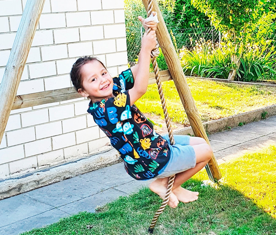 Junge klettert auf ein small foot Kletterseil auf einem Spielplatz.