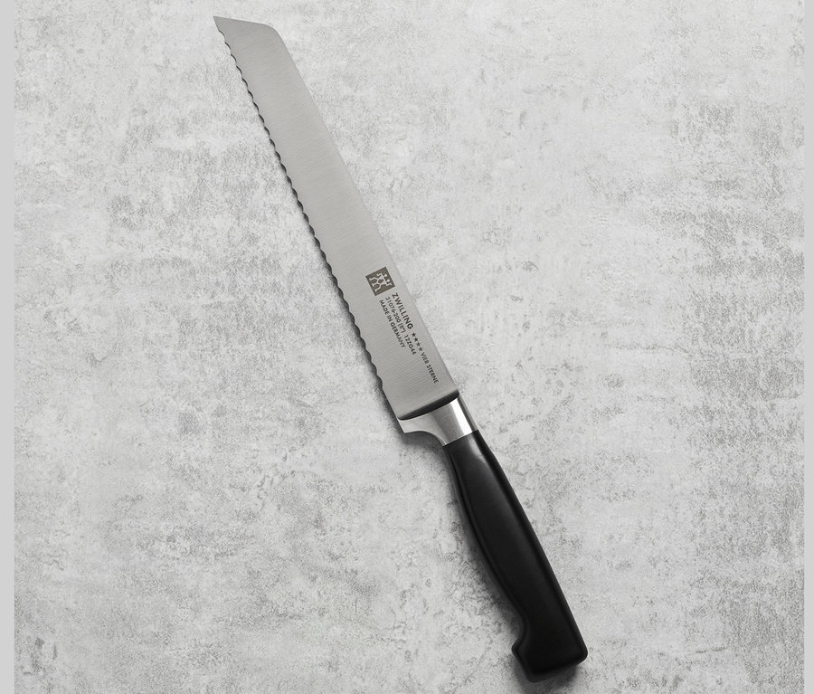 Nahaufnahme eines ZWILLING Brotmessers mit schwarzem Griff auf grauem Hintergrund.