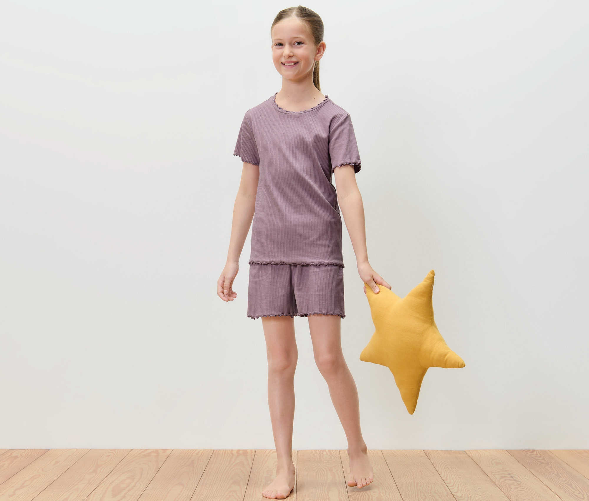 Mädchen im kurzen Kinder-Pyjama hält gelben Stern.