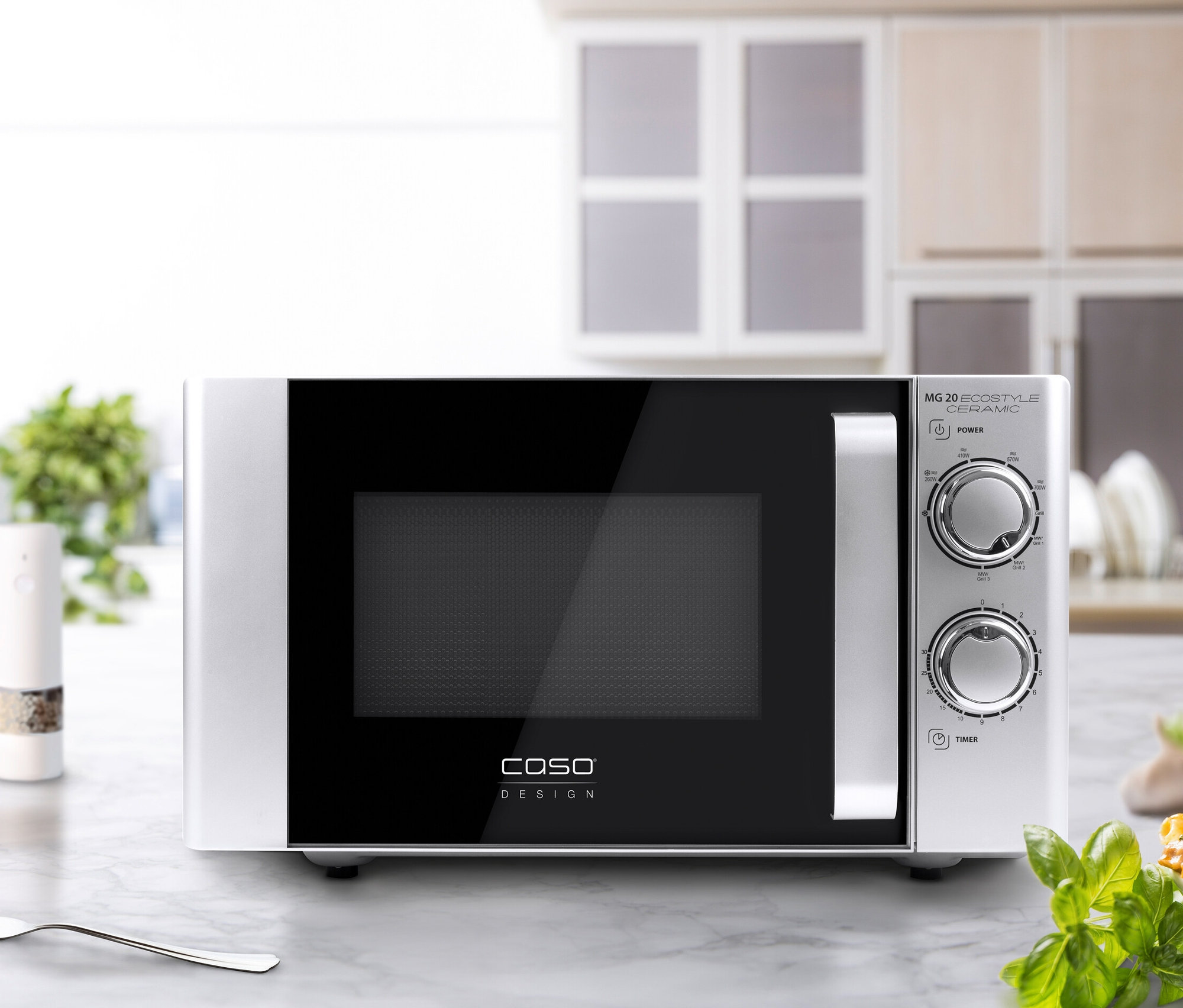 Silberne Caso Mikrowelle steht auf einer Marmorplatte neben einer Gabel und einem Teller Pasta.