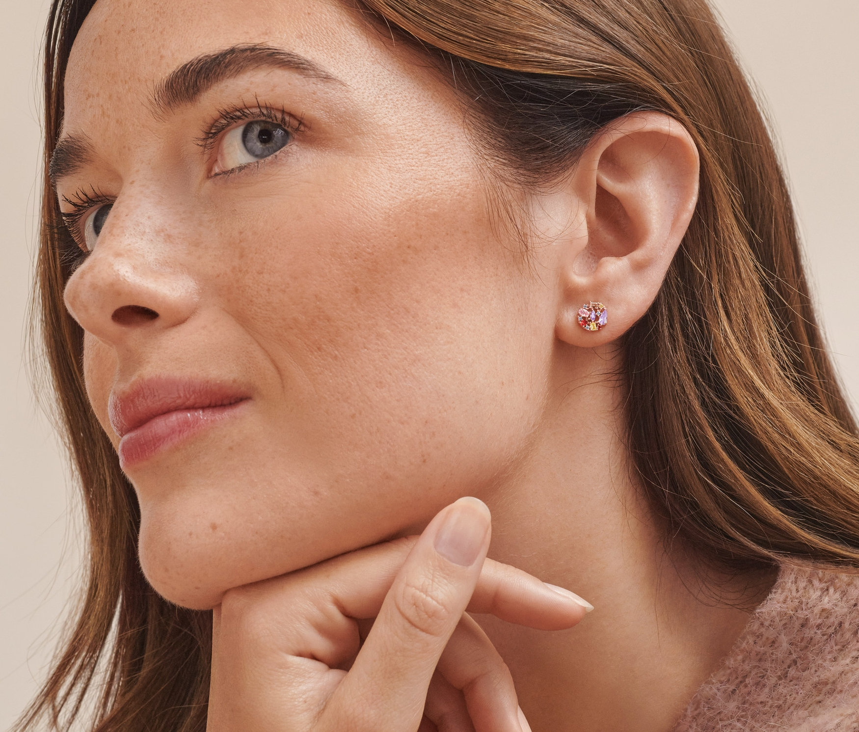 Detailaufnahme vom Gesicht einer Frau, die rosévergoldete Ohrstecker aus 925er Silber mit bunten Zirkonia trägt.