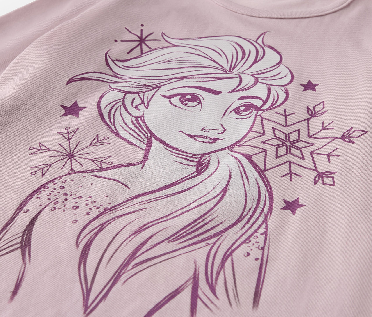 Detailansicht des Kinder-Pyjama-Sets »Eisprinzessin« mit einer gezeichneten Elsa, Schneeflocken und Sternen auf einem rosa T-Shirt.