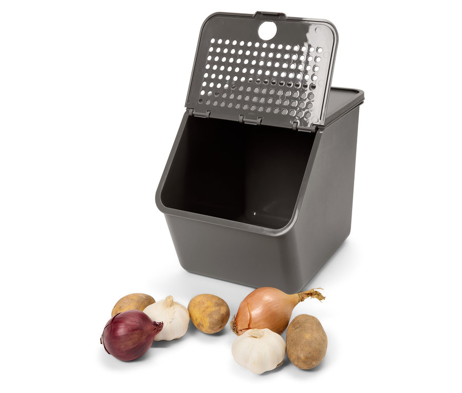 Grauer Behälter mit offenem Deckel und Kartoffeln, Zwiebeln und Knoblauch davor.
