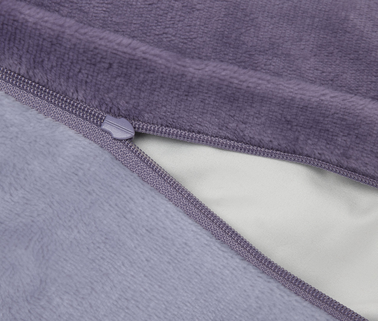 Detailaufnahme eines lila Plüschkissens mit geöffnetem Reißverschluss.