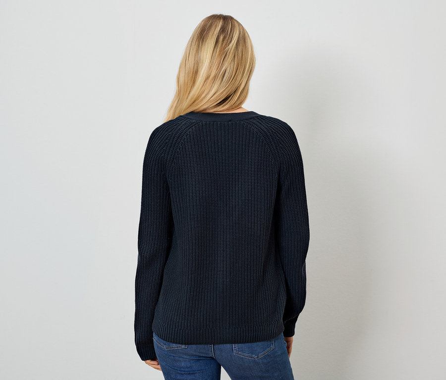 Frau mit dem Rücken zur Kamera trägt einen dunkelblauen Pullover und Jeans.
