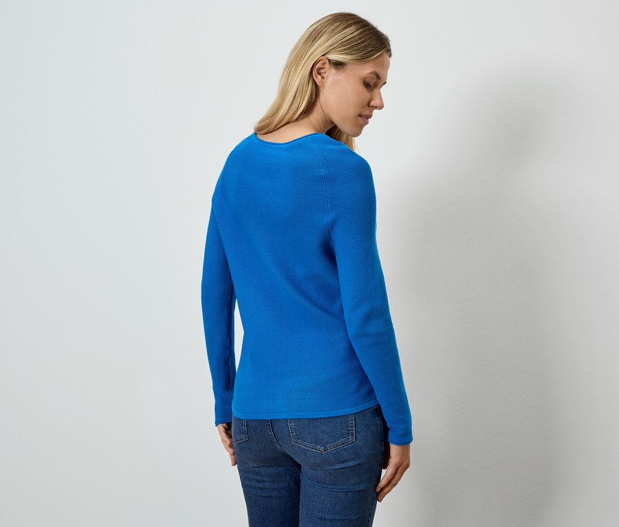 Eine von hinten gezeigte Frau trägt ein blaues Oberteil und Jeans.