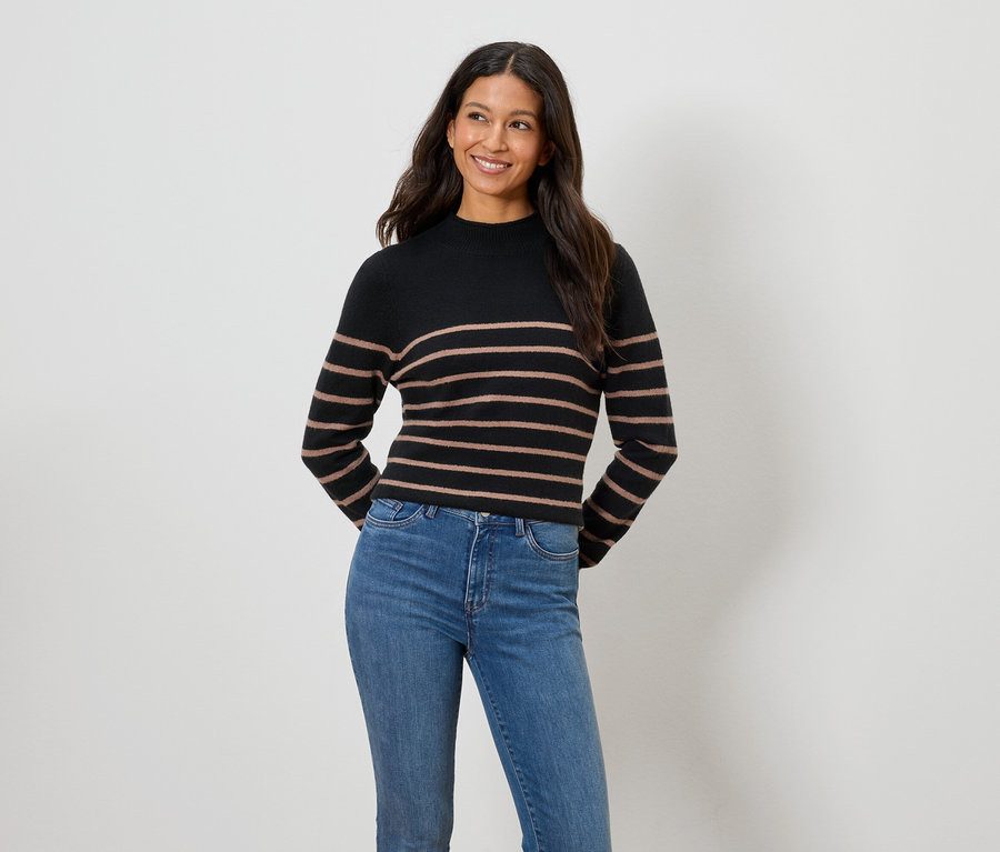 Frau trägt einen schwarz-braun gestreiften Pullover und blaue Jeans.
