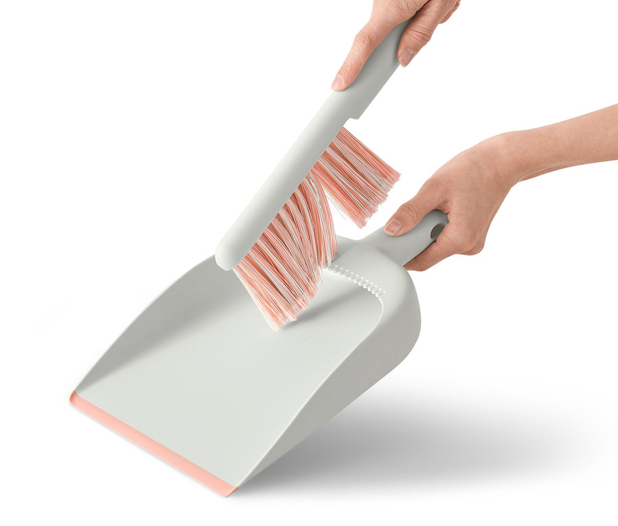 Hände halten Handkehrer und Schaufel.