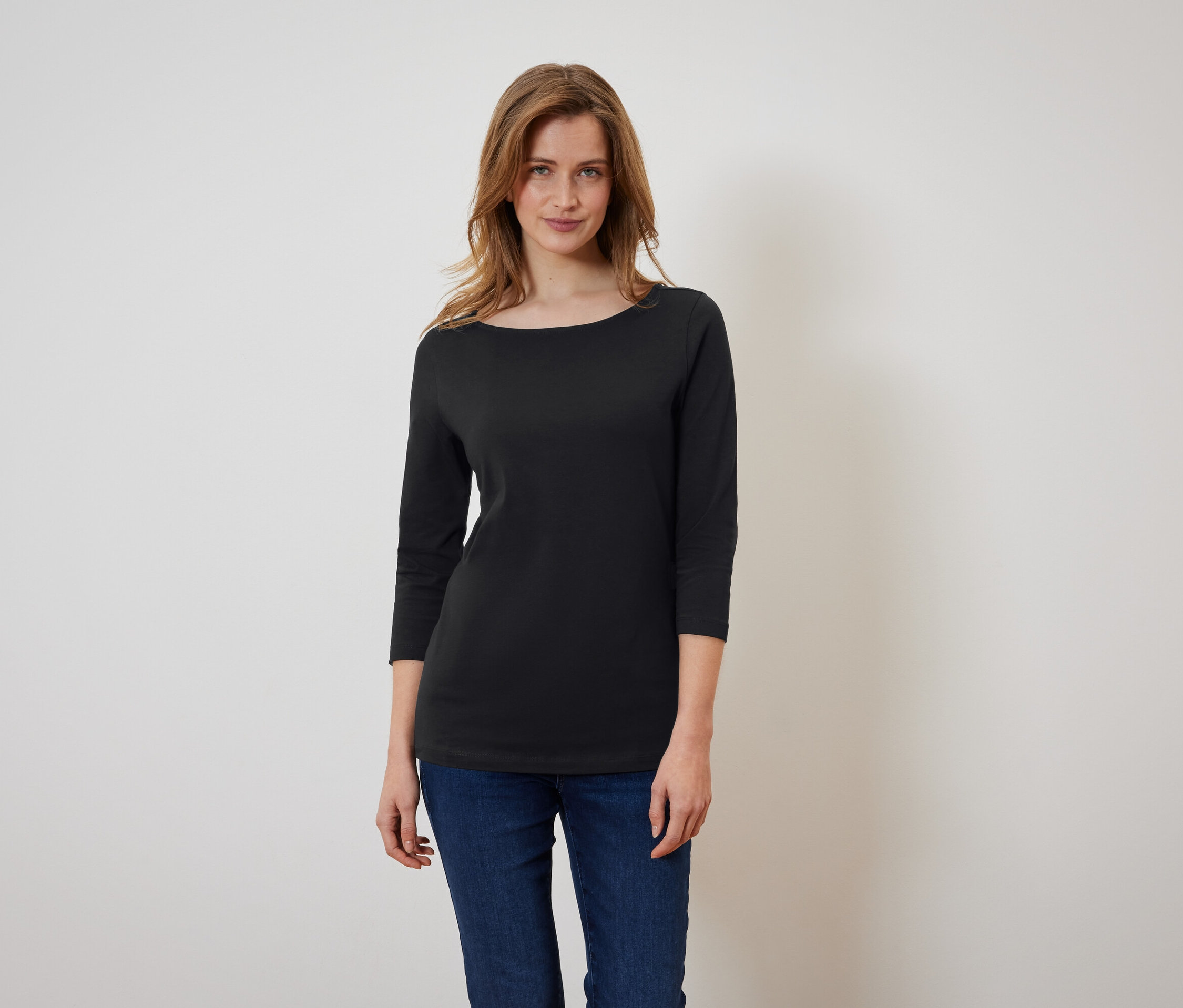 Frau trägt ein schwarzes Dreiviertelarm-Shirt und blaue Jeans.