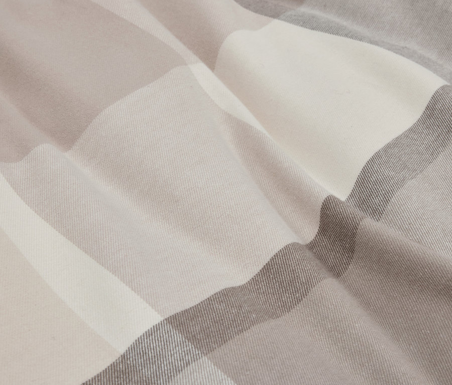 Nahaufnahme eines Stoffes mit einem Karomuster in Beige- und Grautönen.