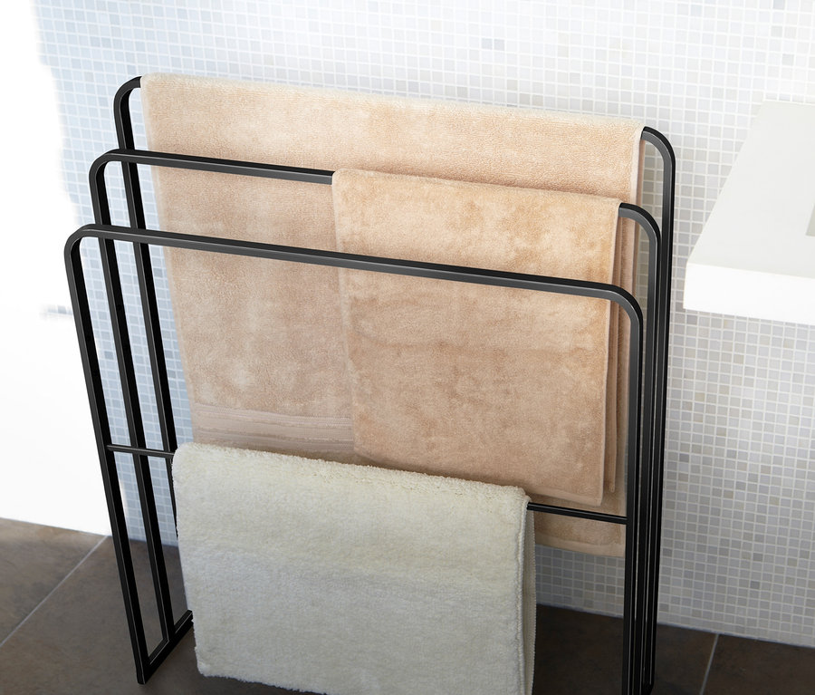 Schwarzer YAMAZAKI Badehandtuch-Ständer »TOWER« mit drei beigen Handtüchern im Badezimmer.