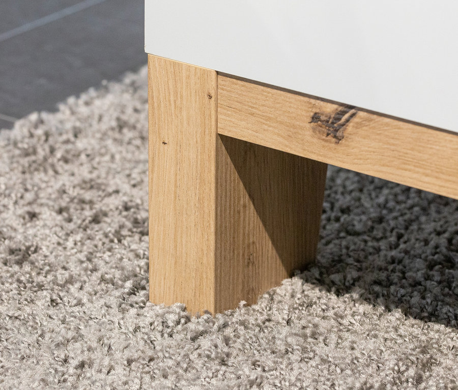 Detail einer Ecke der Rauch Kommode »Credo« in seidengrau auf einem grauen Teppich.