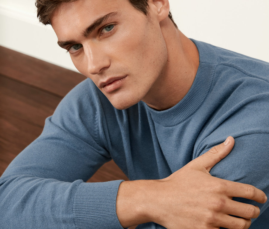Mann trägt blauen Pullover.