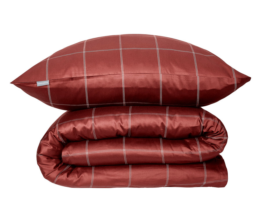 Ein rot kariertes Kissen und eine Bettdecke sind übereinander gestapelt.