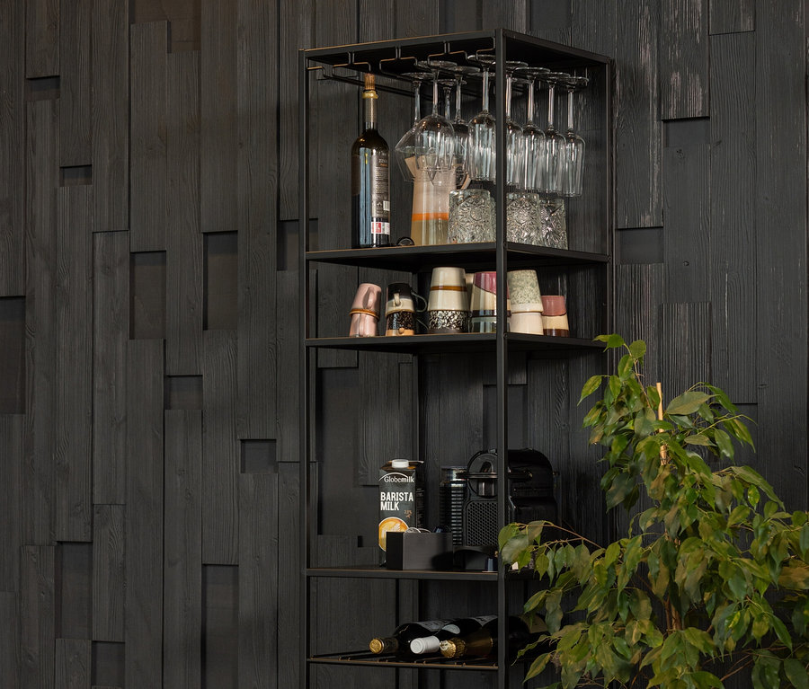 Schwarzes Woood Regal »Reese« aus Metall mit Weinen, Gläsern und Dekorationen steht an der Wand.