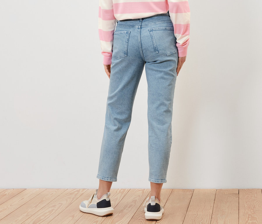 Rückansicht einer Frau in Mom Jeans ‒ Fit »Nyla«, einem gestreiften Oberteil und Turnschuhen.