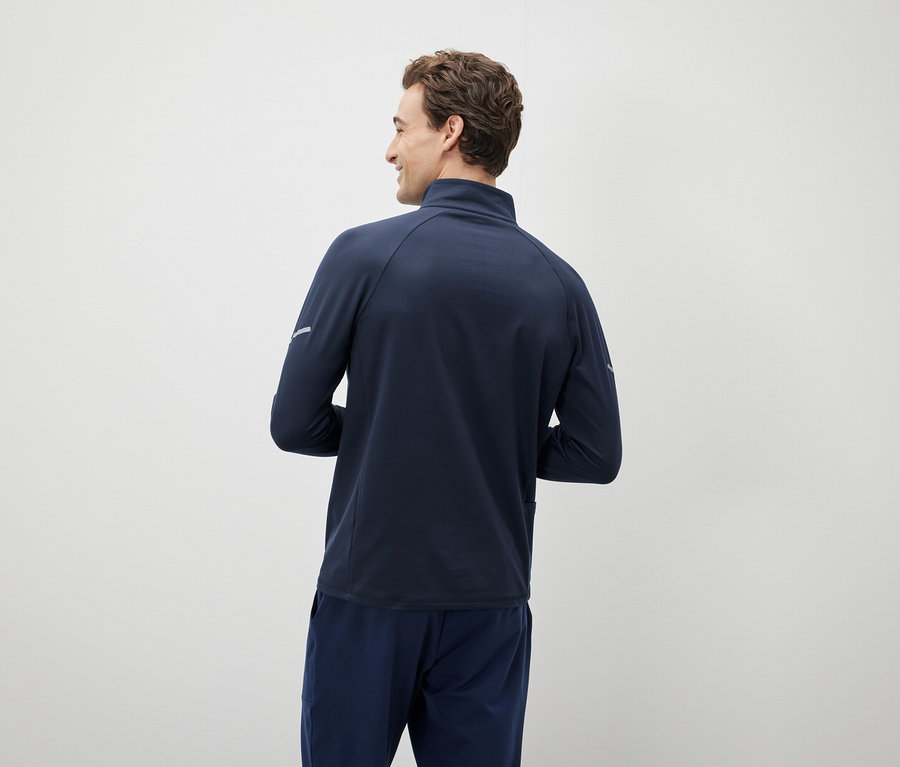 Mann schaut über die Schulter und trägt eine marineblaue Jacke und Hose.