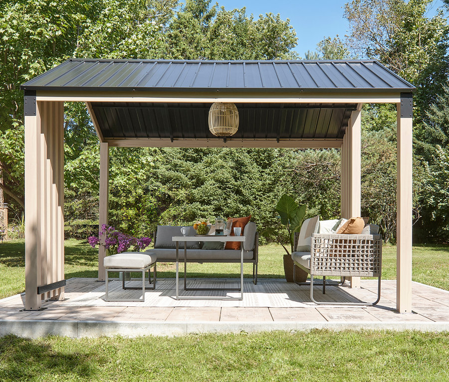 Überdachte Terrasse mit grauen Gartenmöbeln, darunter ein Sofa, ein Sessel und ein Hocker.