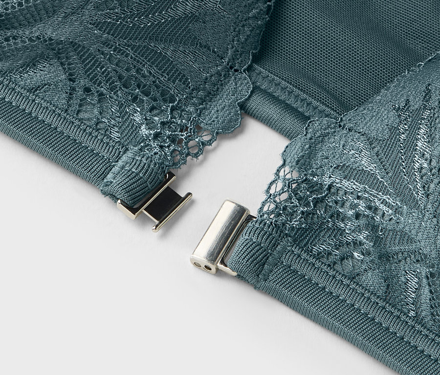 Nahaufnahme von den Details eines türkisfarbenen BHs mit Spitze und silberfarbenem Verschluss.