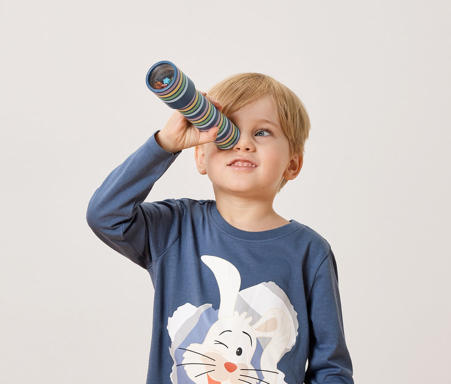 Ein blonder Junge schaut durch ein Kaleidoskop.