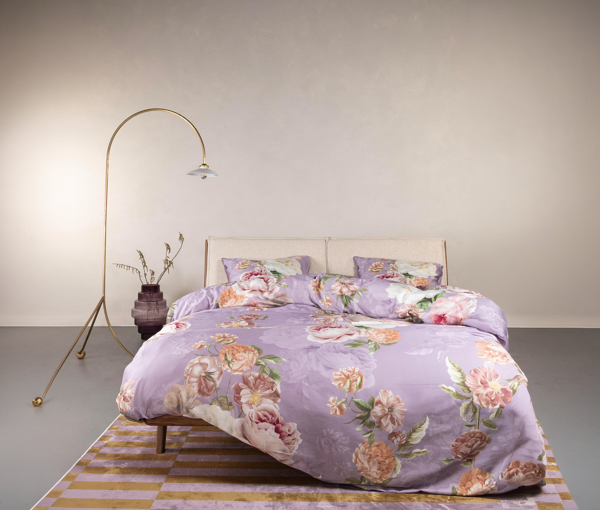 Lila Bettwäsche mit Blumenmuster liegt auf einem Bett mit zwei Kissen.