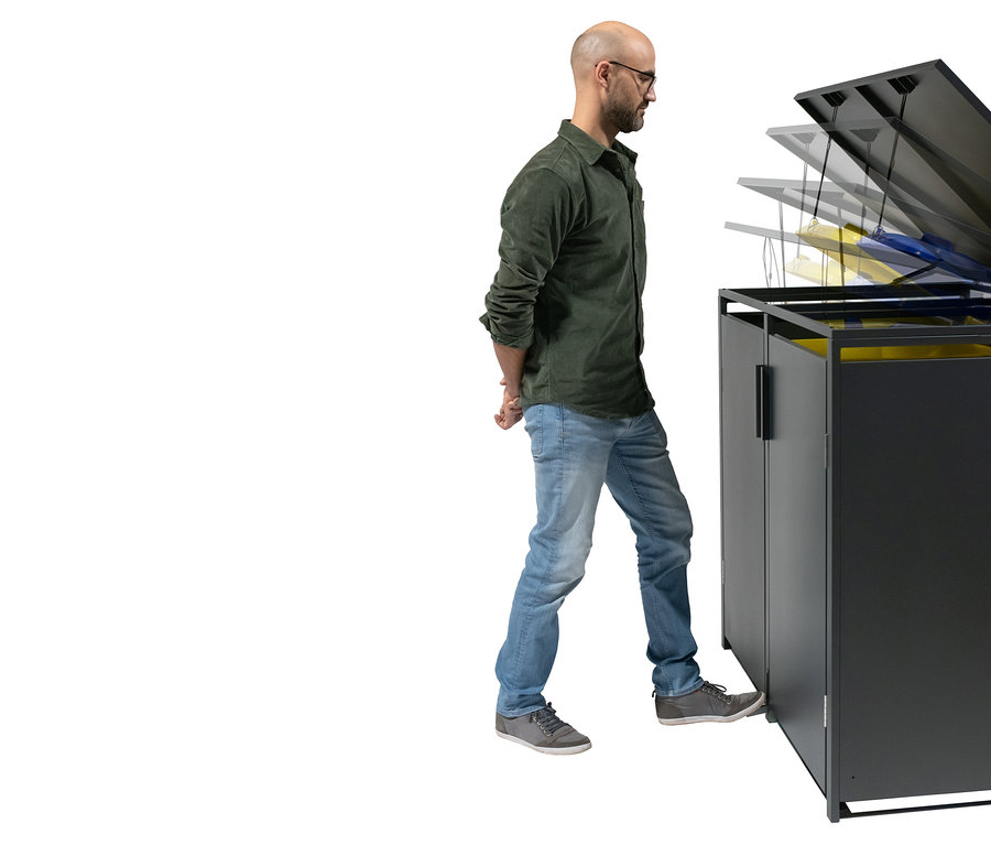 Ein Mann mit Brille öffnet einen schwarzen Mülltonnenschrank mit dem Fuß.