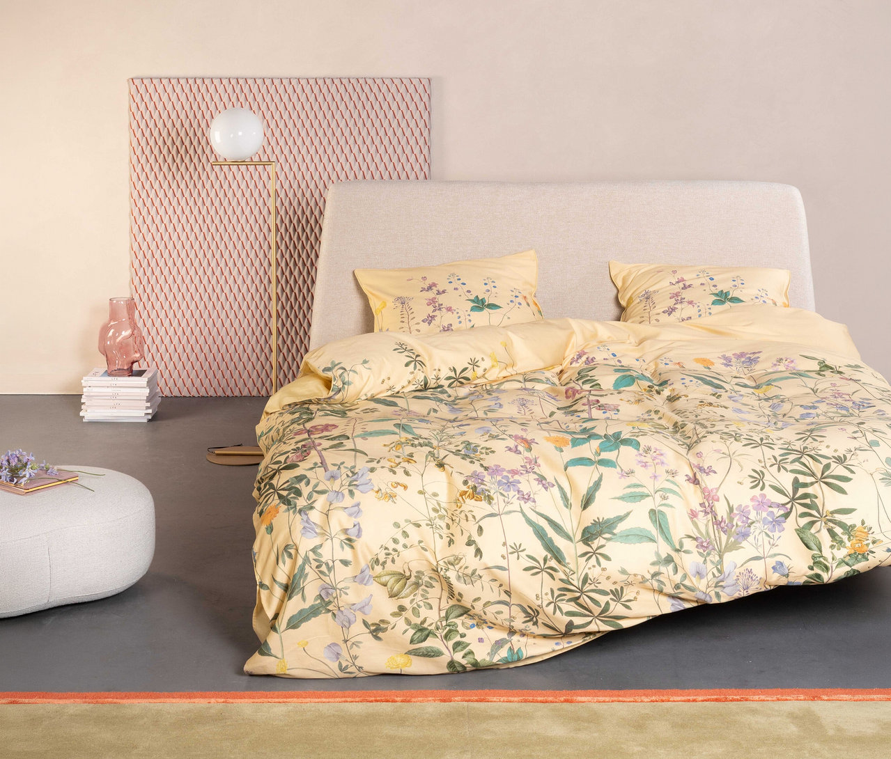 Gelbes Essenza »Augustina« Satin-Bettzeug mit Blumenmuster auf einem Bett mit hellgrauem Kopfteil.