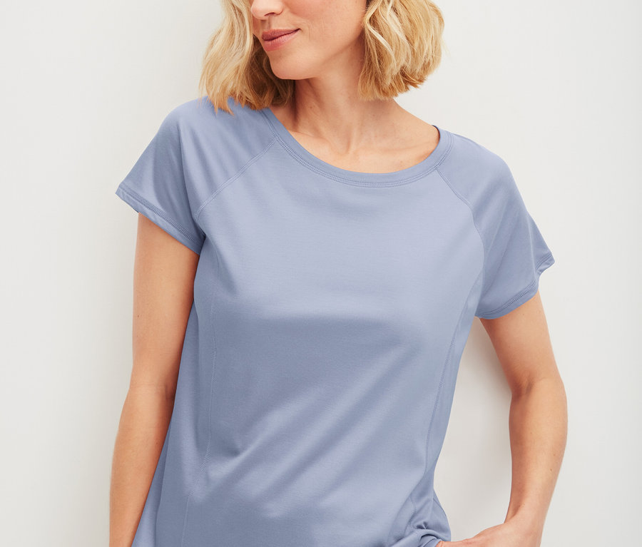 Frau trägt ein hellblaues T-Shirt und Shorts.