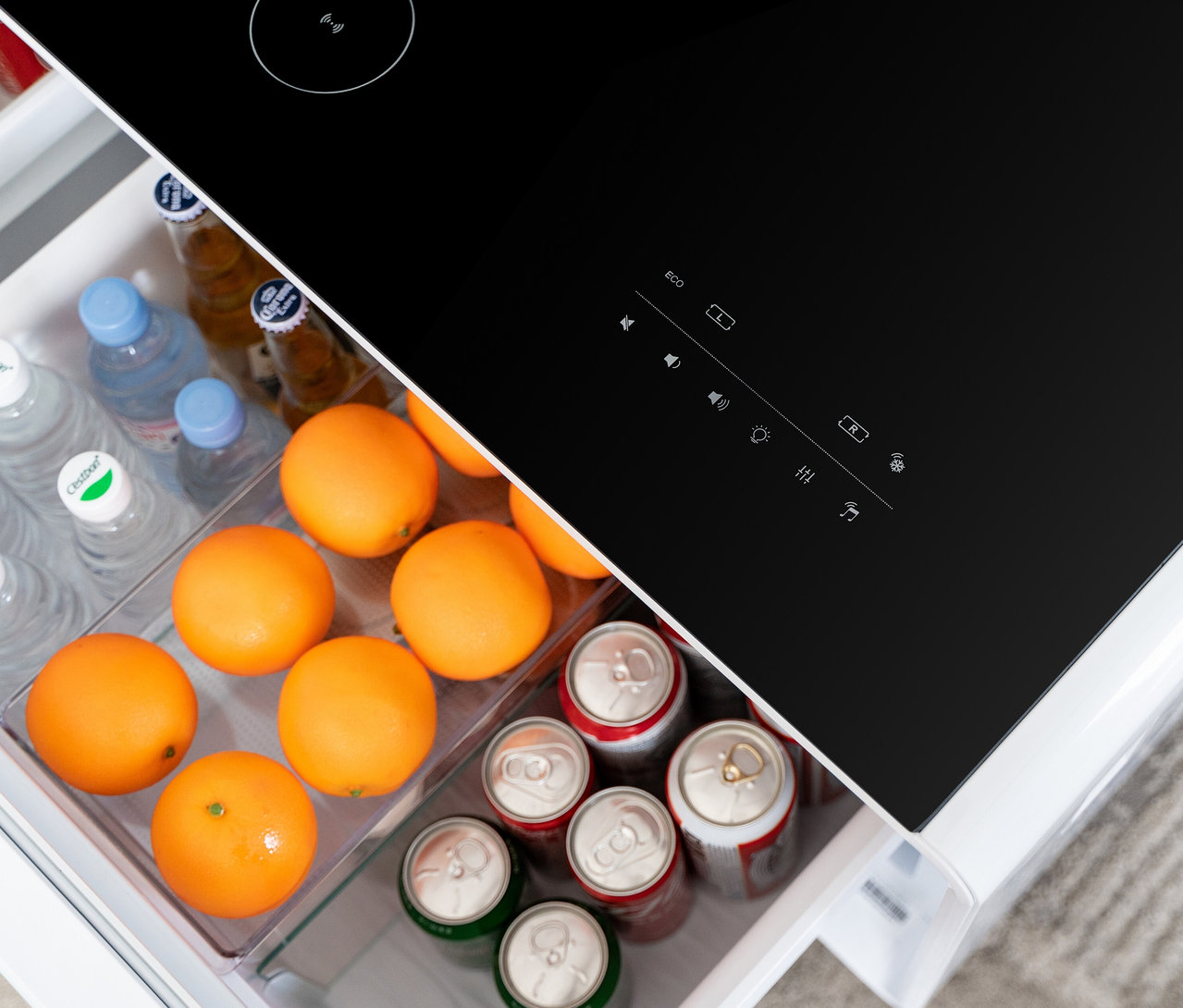 Aufsicht in einen offenen Caso Sound & Cool, weiß Kühlschrank, gefüllt mit Getränken und Orangen.